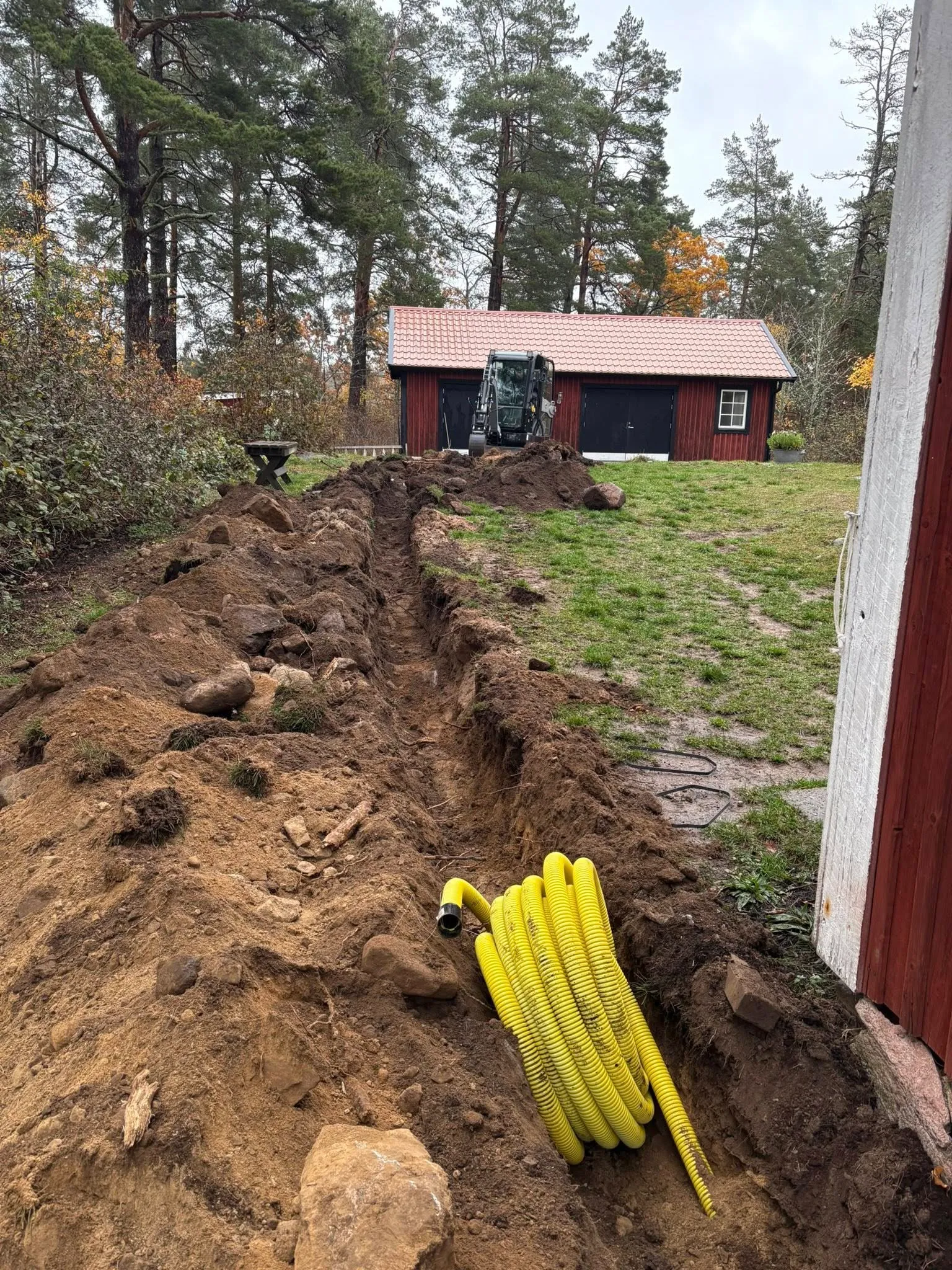 Dränering i Norrköping — schaktning runt husgrund med grävmaskin